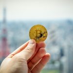 Bitcoin being held out with blurred background | Cryptocurrency applications