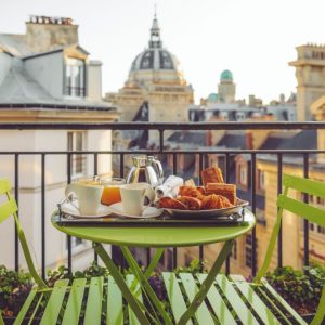 A photo of a bistro table with breakfast sitting on top, on a balcony in Paris, France.